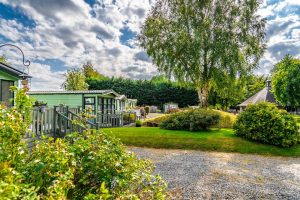 Static holiday home with a garden, decked veranda and shrub borders in summer.