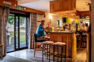 Guests chatting at the bar inside the on-site clubhouse, with draught taps and a warm wood interior.